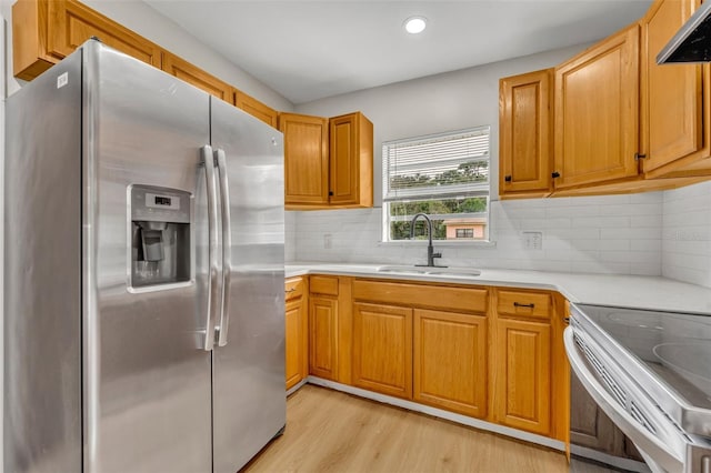 kitchen featuring sink, stainless steel appliances, range hood, light hardwood / wood-style floors, and backsplash