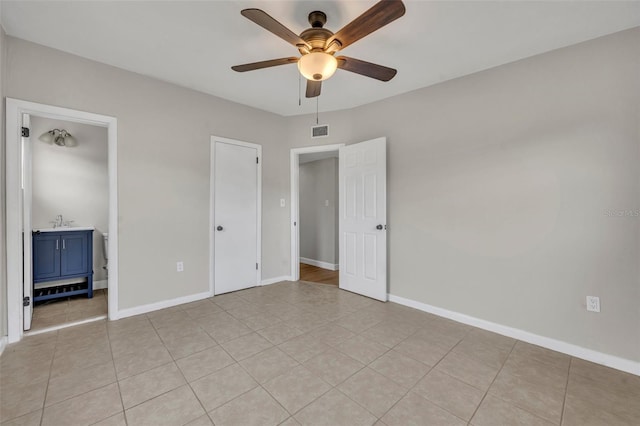 unfurnished bedroom featuring ceiling fan, sink, ensuite bath, and light tile patterned floors