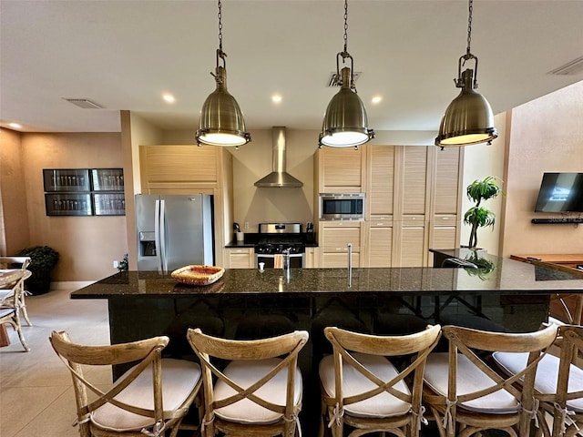 kitchen with stainless steel appliances, a center island with sink, wall chimney range hood, and a breakfast bar