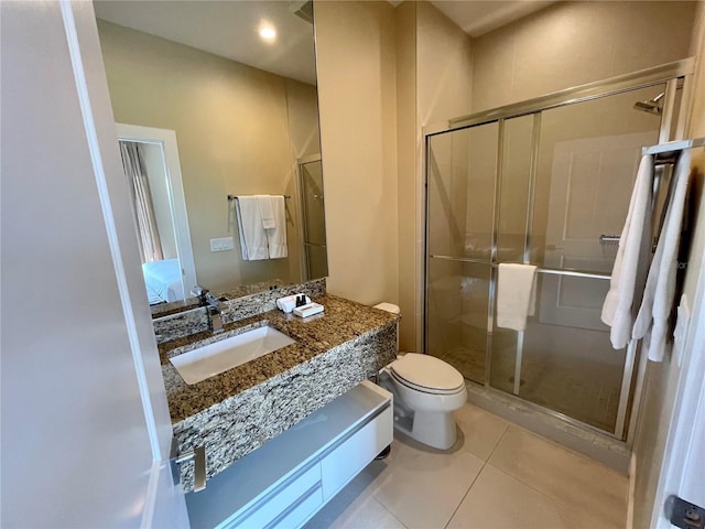 bathroom featuring vanity, a shower with door, tile patterned flooring, and toilet