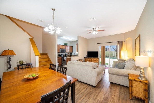 living room with ceiling fan with notable chandelier and hardwood / wood-style flooring