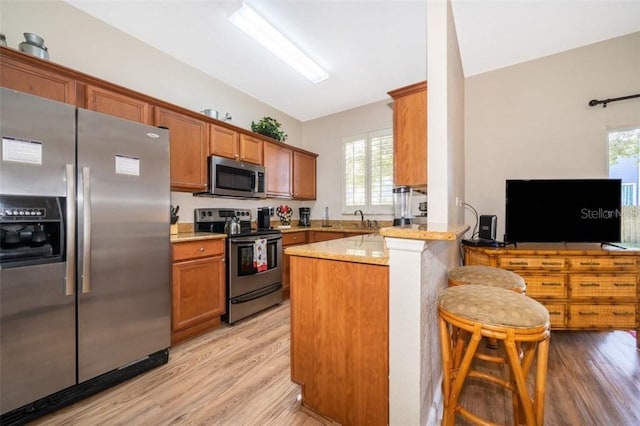 3520 Calabria Ave Unit 3520, Davenport, FL 33897 - kitchen with stainless steel appliances, a peninsula, light wood-style flooring, and brown cabinets