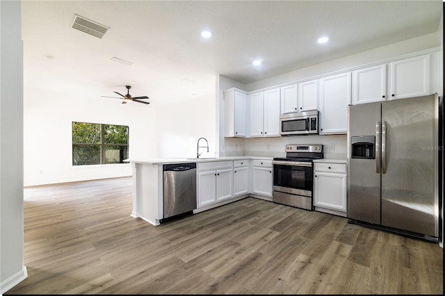 kitchen featuring ceiling fan, kitchen peninsula, appliances with stainless steel finishes, white cabinets, and hardwood / wood-style flooring