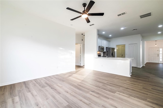 unfurnished living room with ceiling fan and light wood-type flooring