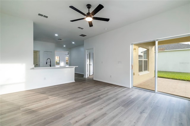 unfurnished living room with light wood-type flooring, ceiling fan, and sink