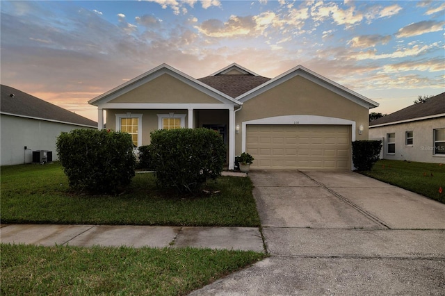 view of front facade featuring a lawn, central AC, and a garage