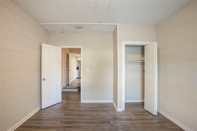 unfurnished bedroom featuring a textured ceiling, a closet, and dark hardwood / wood-style floors