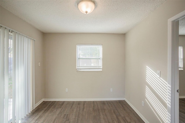 empty room featuring a textured ceiling and dark wood-type flooring