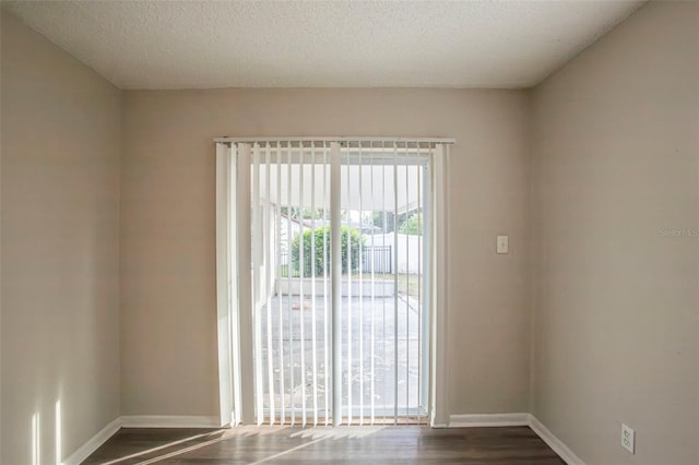 empty room with a textured ceiling and dark wood-type flooring