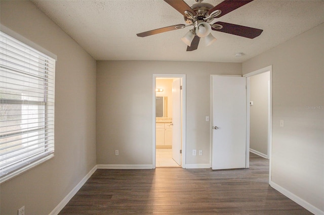 unfurnished bedroom featuring a textured ceiling, ceiling fan, dark wood-type flooring, and ensuite bath