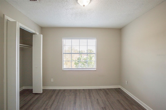 unfurnished bedroom featuring a textured ceiling, dark wood-type flooring, and a closet