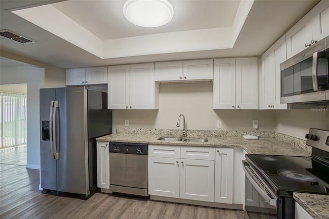 kitchen with stainless steel appliances, a raised ceiling, white cabinetry, and sink