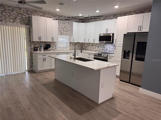 kitchen featuring sink, appliances with stainless steel finishes, an island with sink, white cabinets, and light wood-type flooring