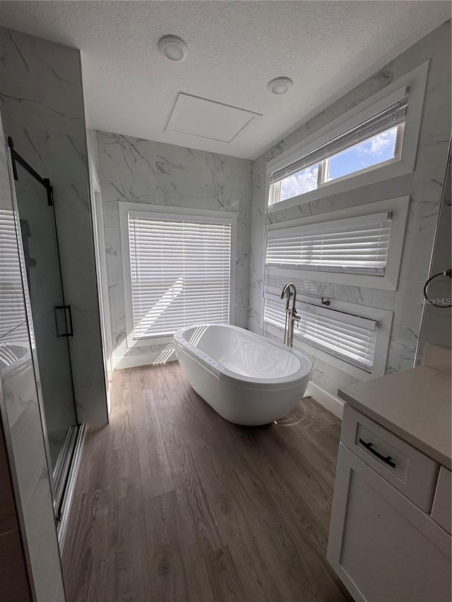 bathroom with shower with separate bathtub, wood-type flooring, a textured ceiling, and vanity