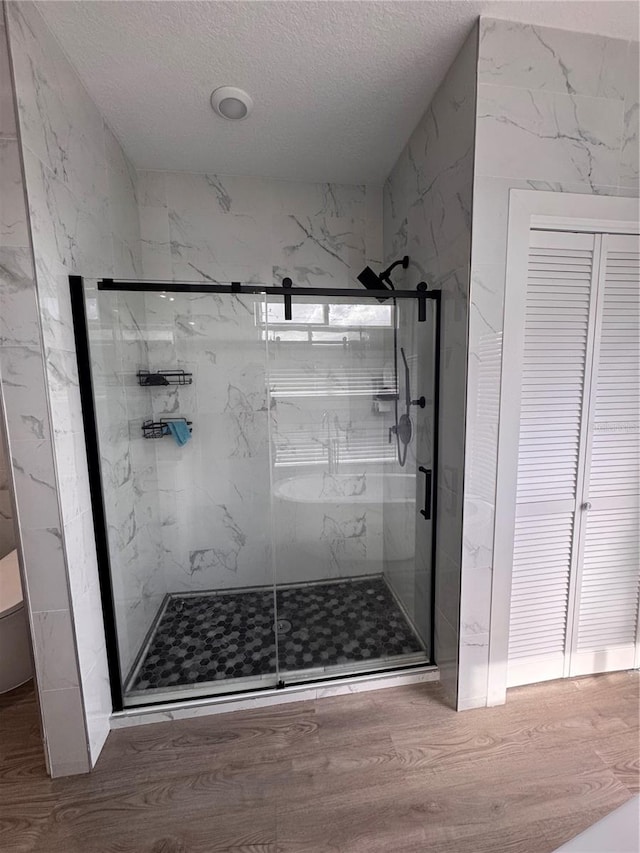 bathroom featuring wood-type flooring, a textured ceiling, and a shower with shower door