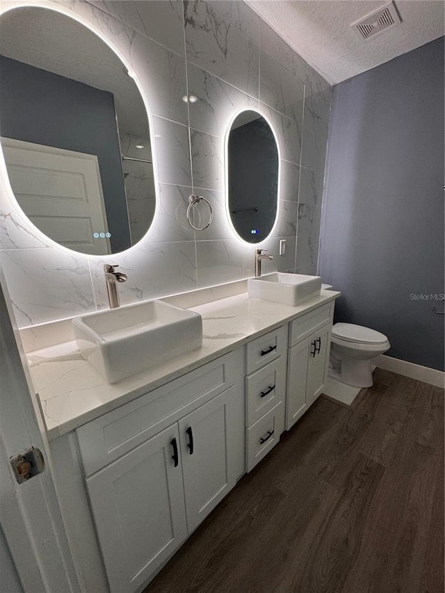 bathroom featuring toilet, vanity, wood-type flooring, and a textured ceiling