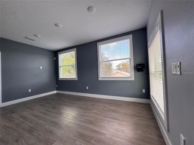 empty room with a textured ceiling and dark hardwood / wood-style floors