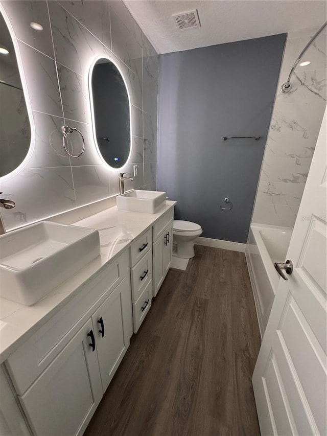 full bathroom with vanity, hardwood / wood-style flooring, toilet, and tub / shower combination