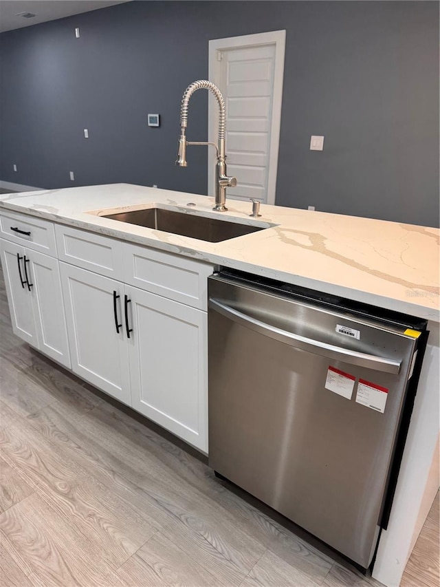 kitchen with stainless steel dishwasher, light hardwood / wood-style floors, light stone countertops, and white cabinets