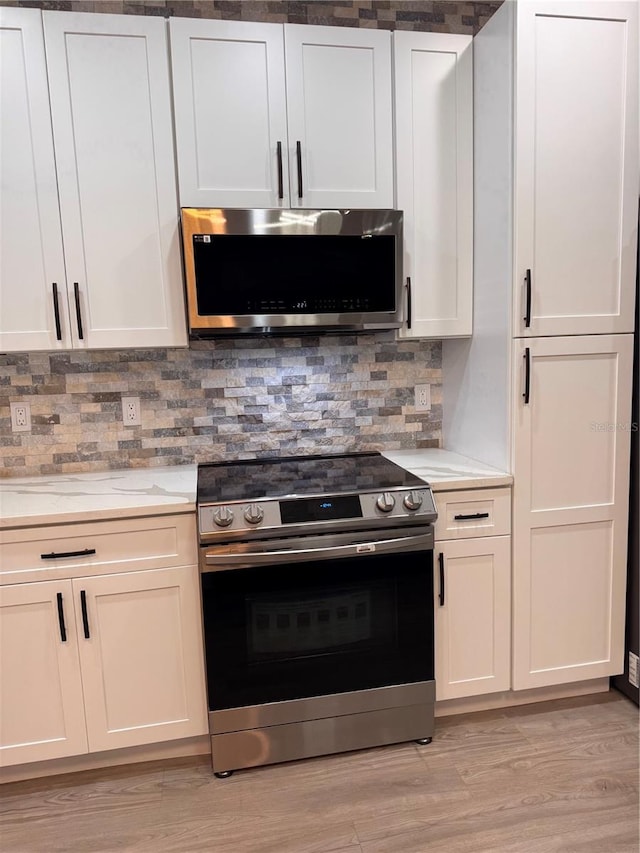 kitchen with light hardwood / wood-style flooring, white cabinetry, backsplash, and stainless steel appliances