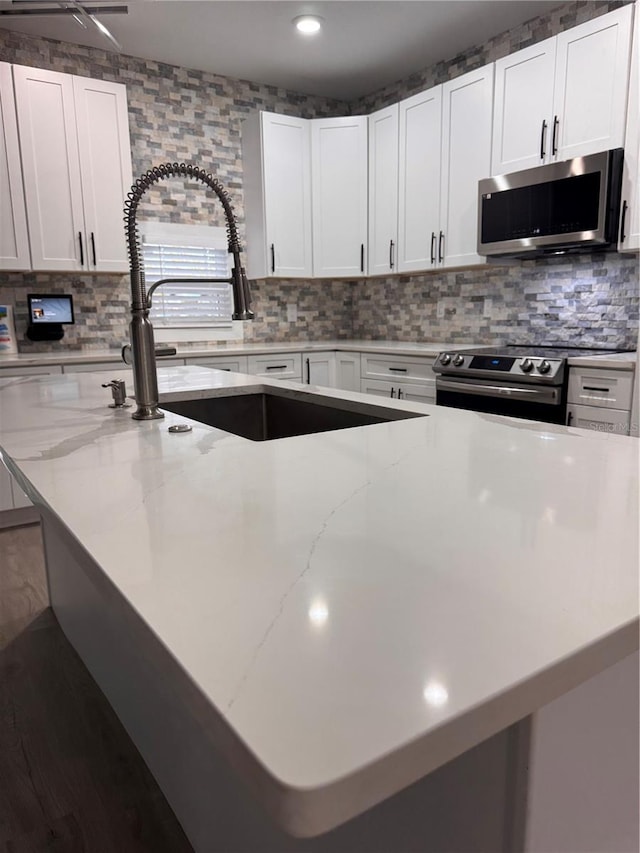 kitchen with white cabinetry, stainless steel appliances, and light stone counters