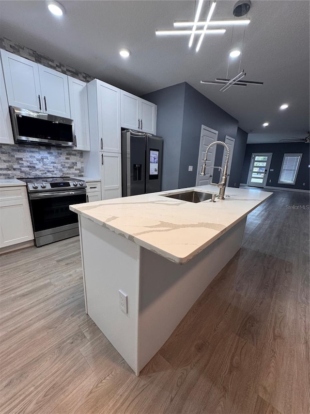 kitchen featuring light wood-type flooring, white cabinetry, a kitchen island with sink, and appliances with stainless steel finishes