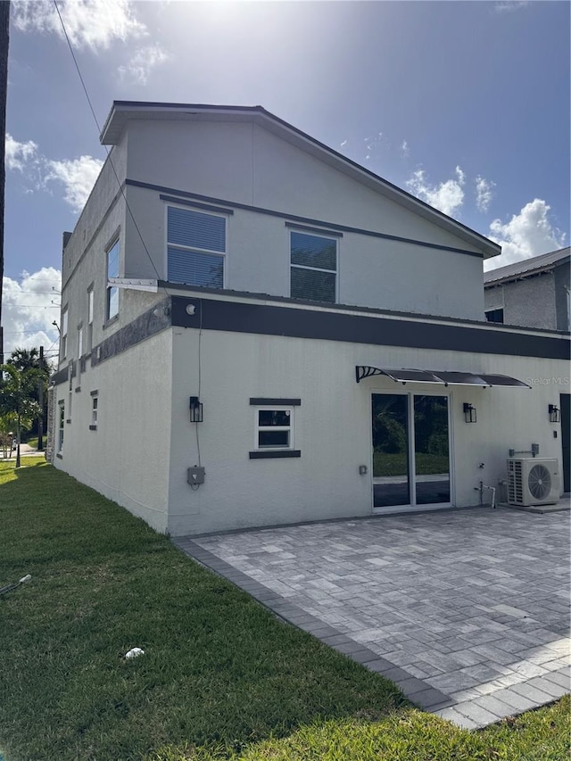 rear view of property with a lawn, ac unit, and a patio area