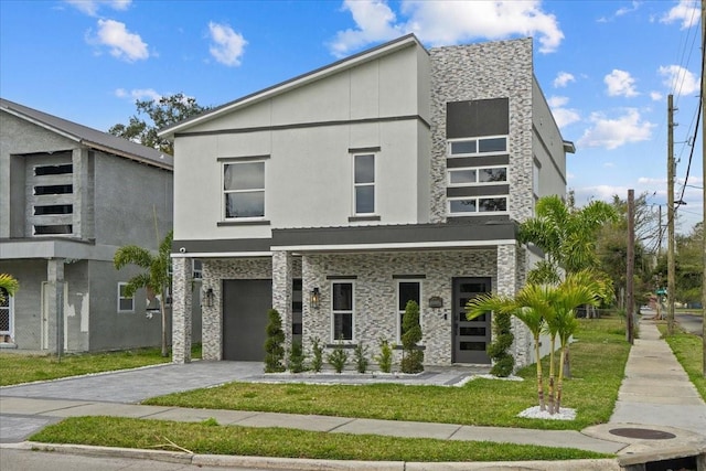 modern home with driveway, a front lawn, an attached garage, and stucco siding