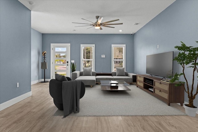 living area with visible vents, wood finished floors, a ceiling fan, and baseboards