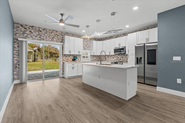 kitchen with stainless steel appliances, light countertops, a sink, and white cabinetry