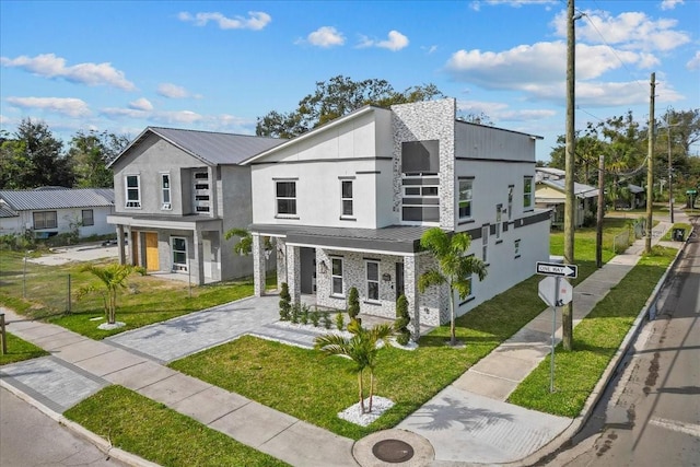 view of front of home featuring stone siding, metal roof, a front lawn, and stucco siding