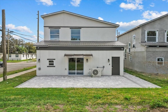 rear view of house with metal roof, a lawn, stucco siding, ac unit, and a patio area