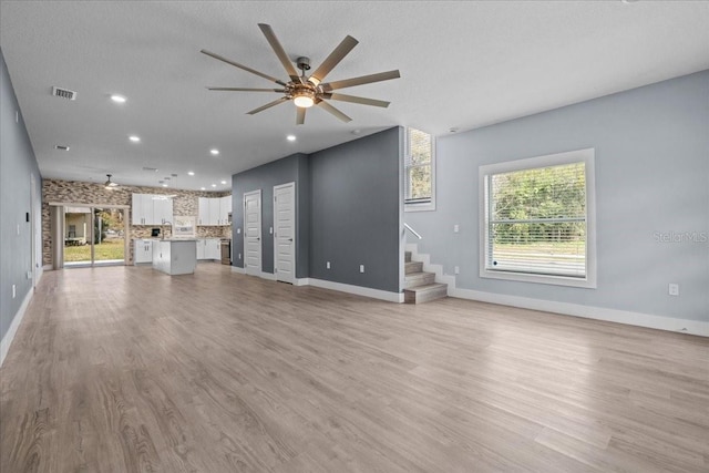 unfurnished living room featuring light wood finished floors, visible vents, ceiling fan, stairs, and recessed lighting