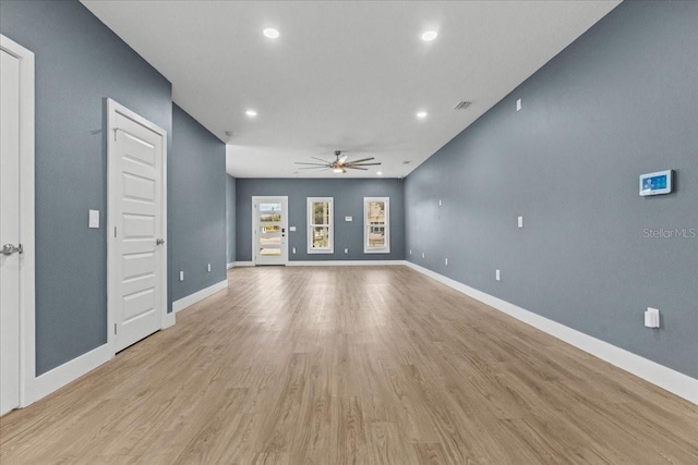 unfurnished living room with ceiling fan, light wood finished floors, visible vents, and baseboards