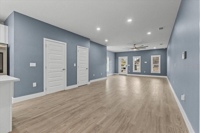 unfurnished living room with light wood finished floors, ceiling fan, visible vents, and baseboards