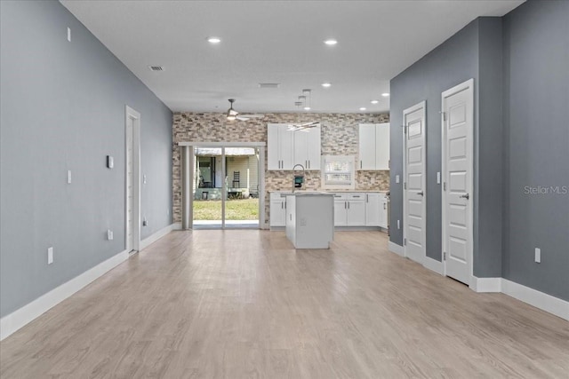 unfurnished living room featuring light wood-style flooring, visible vents, baseboards, and a ceiling fan