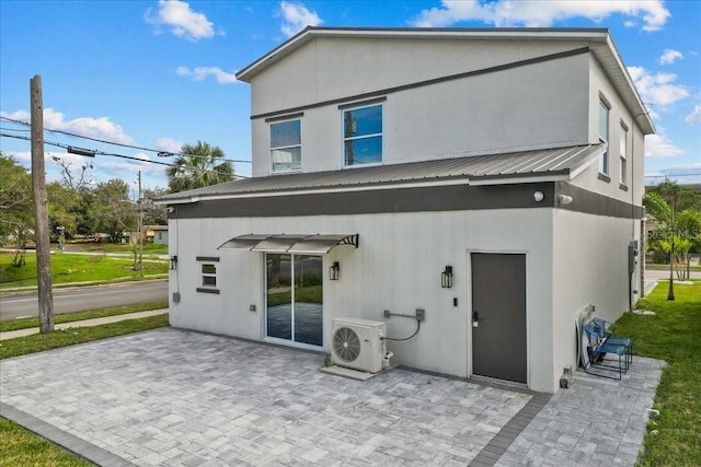 rear view of house featuring a patio area, stucco siding, metal roof, and ac unit