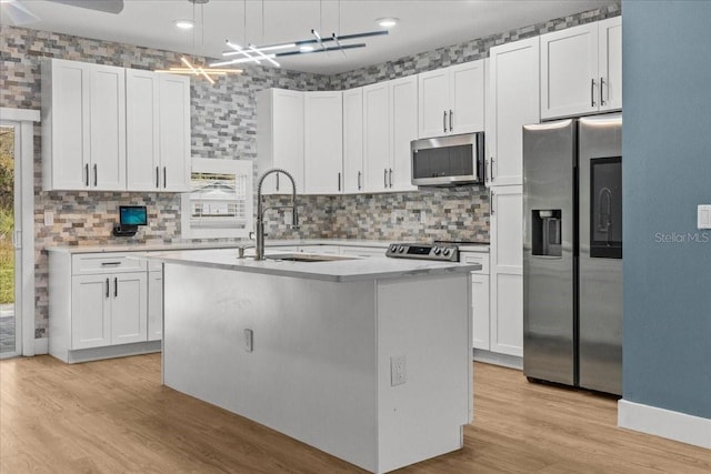 kitchen featuring an island with sink, light wood-style flooring, appliances with stainless steel finishes, light countertops, and a sink