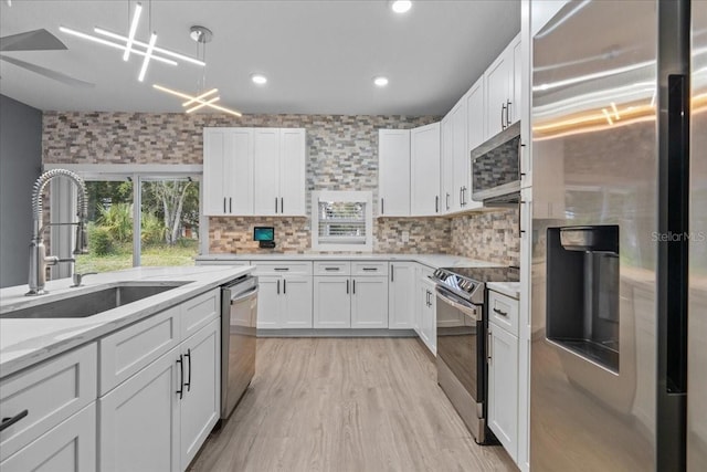 kitchen featuring light stone counters, a sink, white cabinetry, appliances with stainless steel finishes, and tasteful backsplash