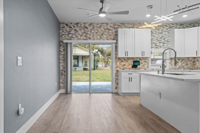 kitchen featuring white cabinets, light wood-style flooring, light countertops, and a sink