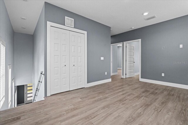 unfurnished bedroom with baseboards, visible vents, and wood finished floors