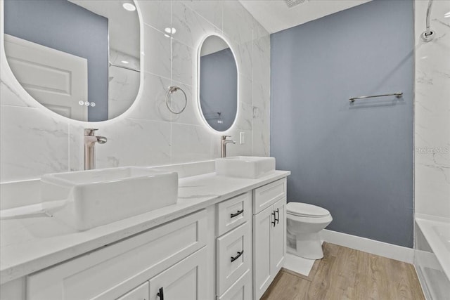 full bath with toilet, a tub, a sink, and wood finished floors