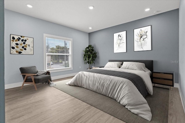 bedroom featuring baseboards, wood finished floors, and recessed lighting