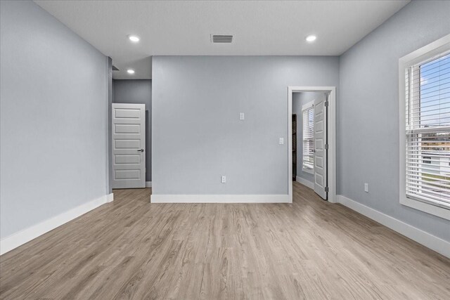 empty room with baseboards, visible vents, wood finished floors, and recessed lighting