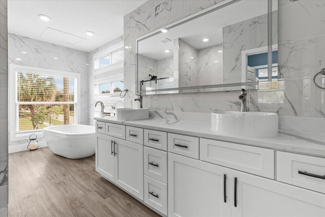 full bathroom featuring double vanity, wood finished floors, a sink, and tile walls