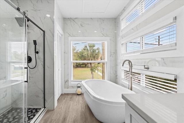 full bathroom with wood finished floors, a soaking tub, and a marble finish shower