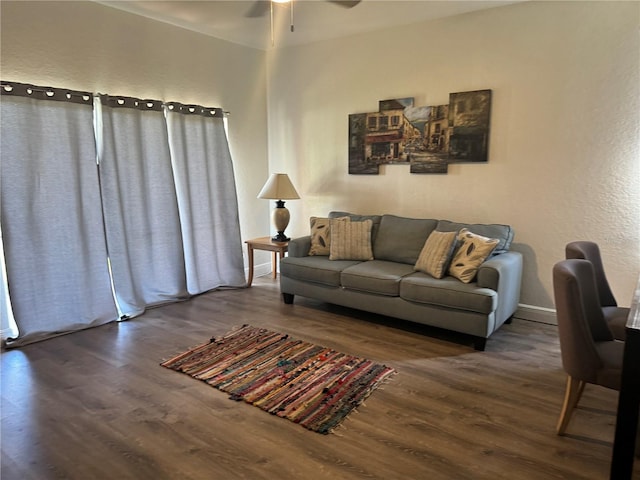 living room featuring dark wood-type flooring and ceiling fan