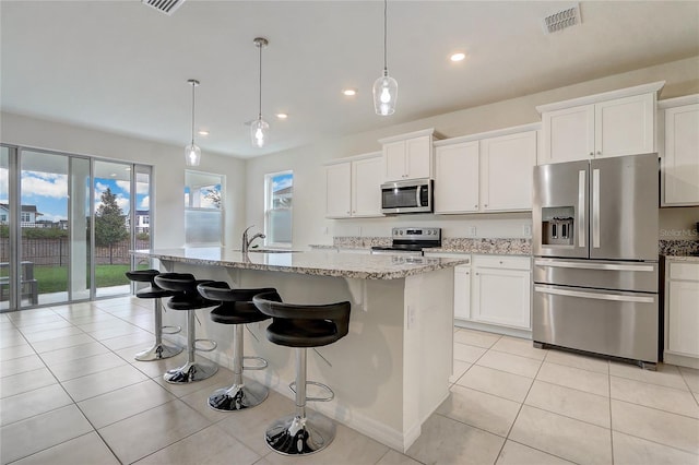 kitchen with a kitchen island with sink, plenty of natural light, pendant lighting, and appliances with stainless steel finishes