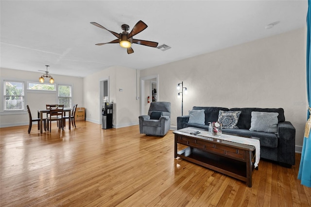 living room with light wood-type flooring and ceiling fan with notable chandelier