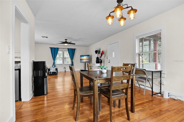 dining room featuring ceiling fan with notable chandelier and light hardwood / wood-style flooring